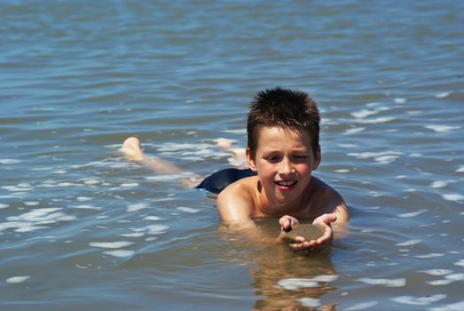 Boy playing with sand in the sea.