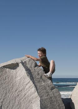 Young boy climbing rocks at the beach