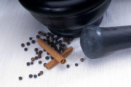 black stone mortar and pestel with cinnamon and pepper