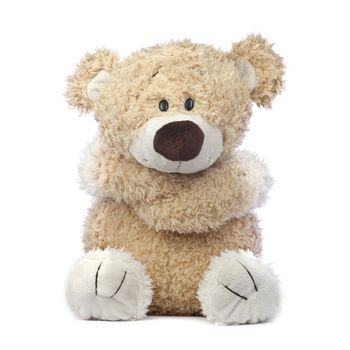 An adorable teddy bear that is cold, sad and hurt, hugging himself.