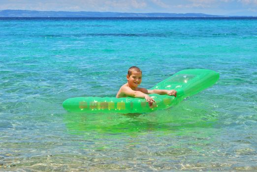 Happy boy in the sea playing with a pool float.