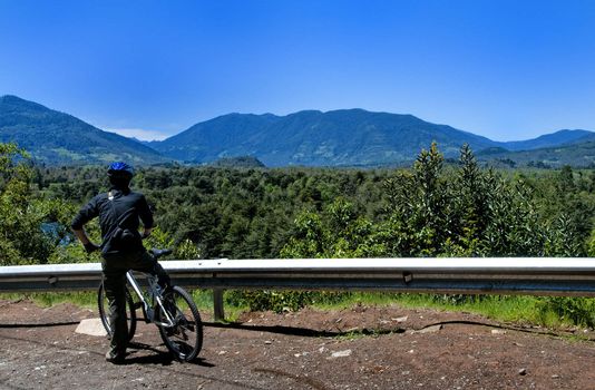 Man on bicycle admiring the landscape on the outskirts of pucon, Chile