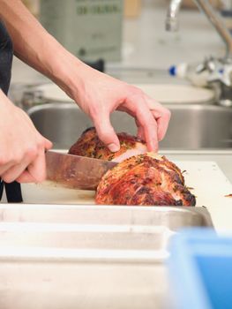 Chef cutting roast ham in a  kitchen