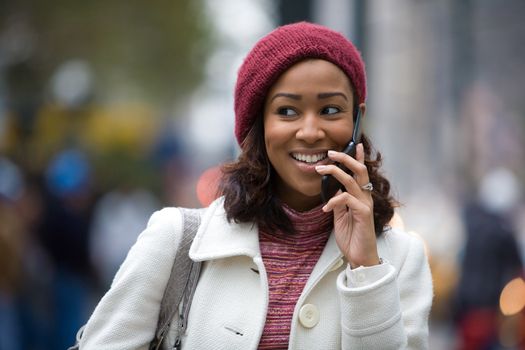 An attractive business woman talks on her cell phone as she walks through the city.