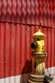 Street water pump next to a red metal wall in Valpariso, Chile 