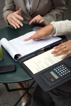 Two women having a discussion and sharing information during a business meeting.  Shallow depth of field.