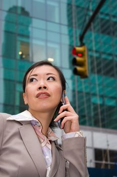 An attractive Asian business woman talking on her cell phone in the city.