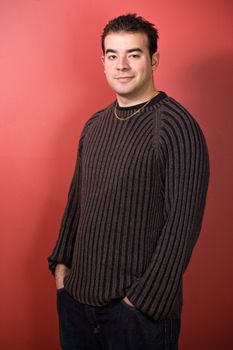 Portrait of a young man in his twenties over a red background.