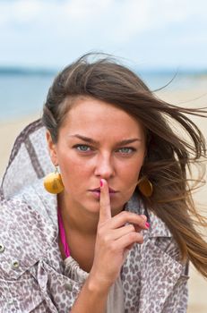 Young attractive woman with his finger around his lips. Portrait of a Woman. Outdoor, summer.