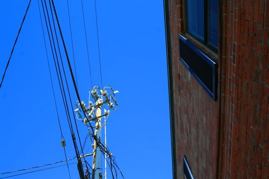 Close up of an electricity pole over blue sky.