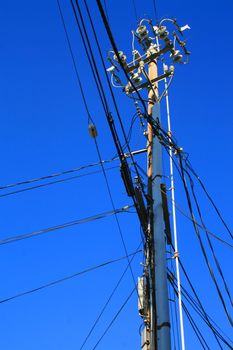 Close up of an electricity pole over blue sky.