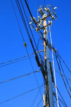 Close up of an electricity pole over blue sky.