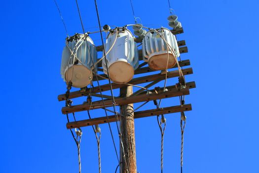 Close up of an electricity transformer over blue sky.
