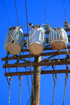 Close up of an electricity transformer over blue sky.
