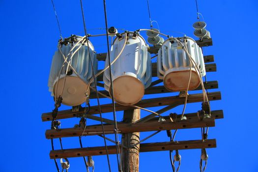 Close up of an electricity transformer over blue sky.

