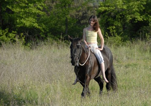 smiling young woman and her best friend black stallion in a field