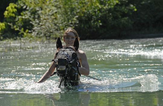 young woman and her black stallion in a river