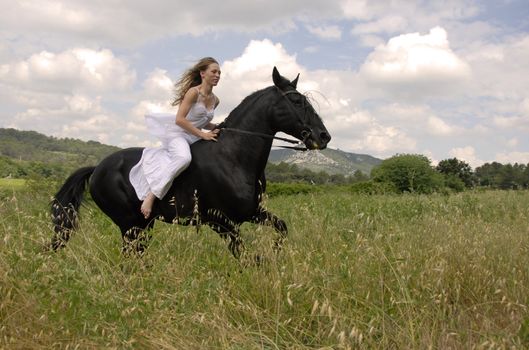 galloping beautiful wedding woman on her black stallion. photo with orange filter