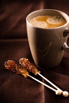 A cup of freshly made coffee with sugar sticks