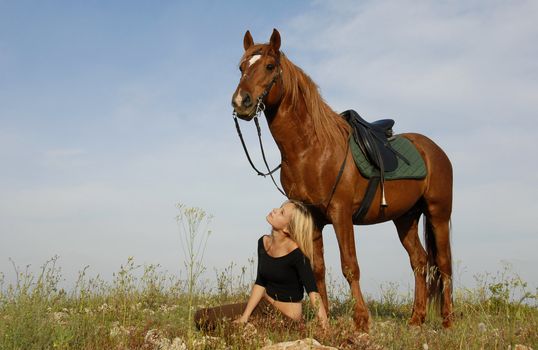 blond teenager and her brown horse in a field