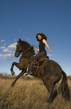 rearing black stallion and happy young woman in a field