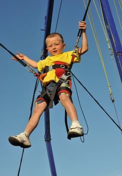 Little boy  jumping on the trampoline (bungee jumping).