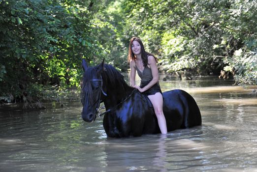 young woman and her black stallion in a river