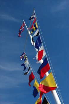Flags. /  On a flagstaff multi-colored flags against the dark blue sky develop on a wind.
