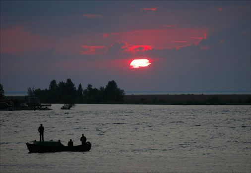 Fishing on a decline. / Decline of summer evening. Fishermen by a boat fish in twilight.