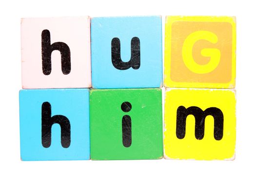 assorted childrens toy letter building blocks against a white background that spell hug him with clipping path