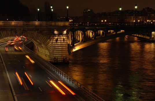 Traffic on a highway at night under a bridge in Paris (France).