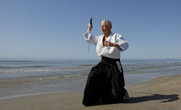 one old man are training in Aikido on the beach