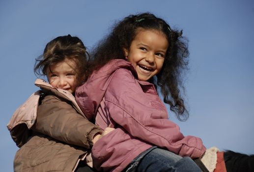 two laughing little girls on a horse : the best friends