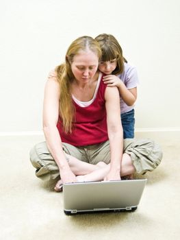 Little girl watching her grandmother using the laptop computer.