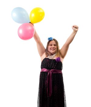 A happy birthday girl with her arms in the air and holding three colored balloons, isolated against a white background