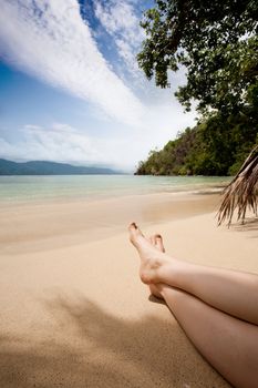 A pair of female legs in the tropics on a beach