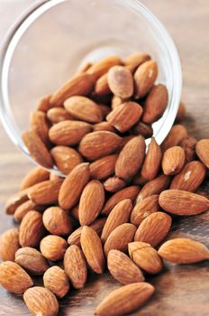 Raw almonds spilling out of small glass bowl