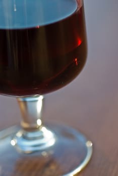 A glass of red wine on a wooden table.