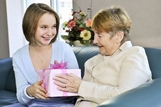 Granddaughter bringing wrapped gift to her grandmother