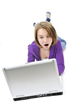 Surprised young girl lying down with laptop computer