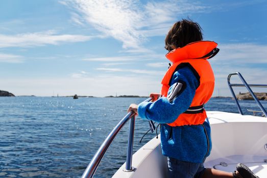 Photo of a 7 year old on a boat trip, gazing into the waters. Sea safety concept.