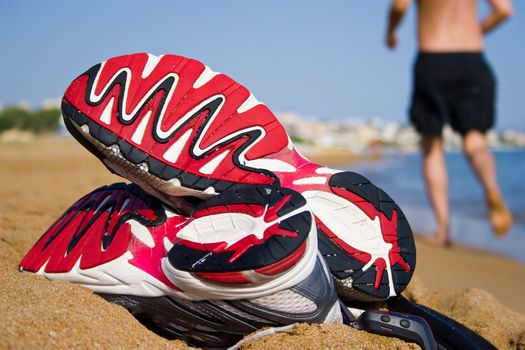 Photograph taken on beach of Greece, sharpness focused on the tip of the shoes. Gear consists of two sports shoes, a GPS unit with a belt.