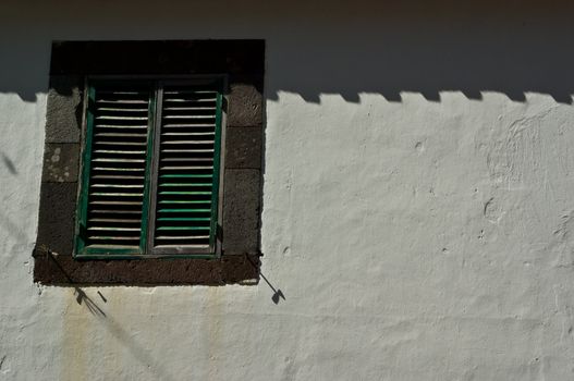 Window with blinds in a white wall, taken on Madeira, Portugal.