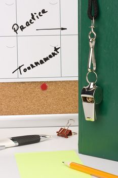 A silver whistle on a green notebook next to a schedule of the tournament.