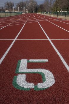 white lane number five at a starting line red running tracks