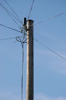 The top of a phone pole with a mess of wires going in different directions.