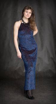 The girl in a dark blue evening dress on a black background