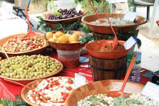 A variety of French delicacies like olives, tapenade and marinated garlic on a local market in Bedoin, France 