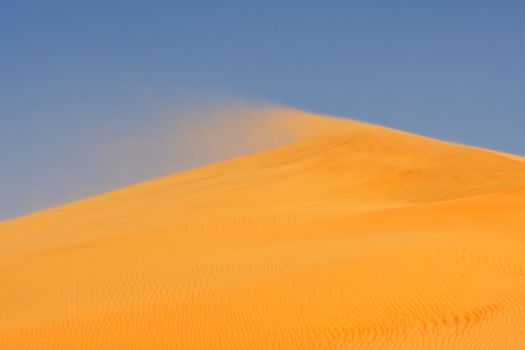 Wind blowing on the crest of a dune in the Rub al Khali or Empty Quarter. Straddling Oman, Saudi Arabia, the UAE and Yemen, this is the largest sand desert in the world.