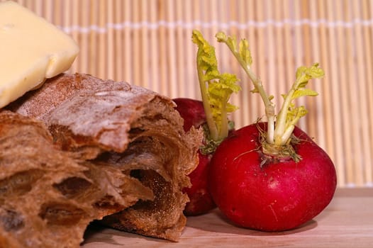 Still-life with ciabatta, redish and cheese on wooden plate